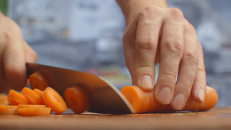 Woman-cutting-carrot-on-table-closeup